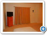 Master Bedroom view to TV and to curtains hiding sliding doors to outside patio.